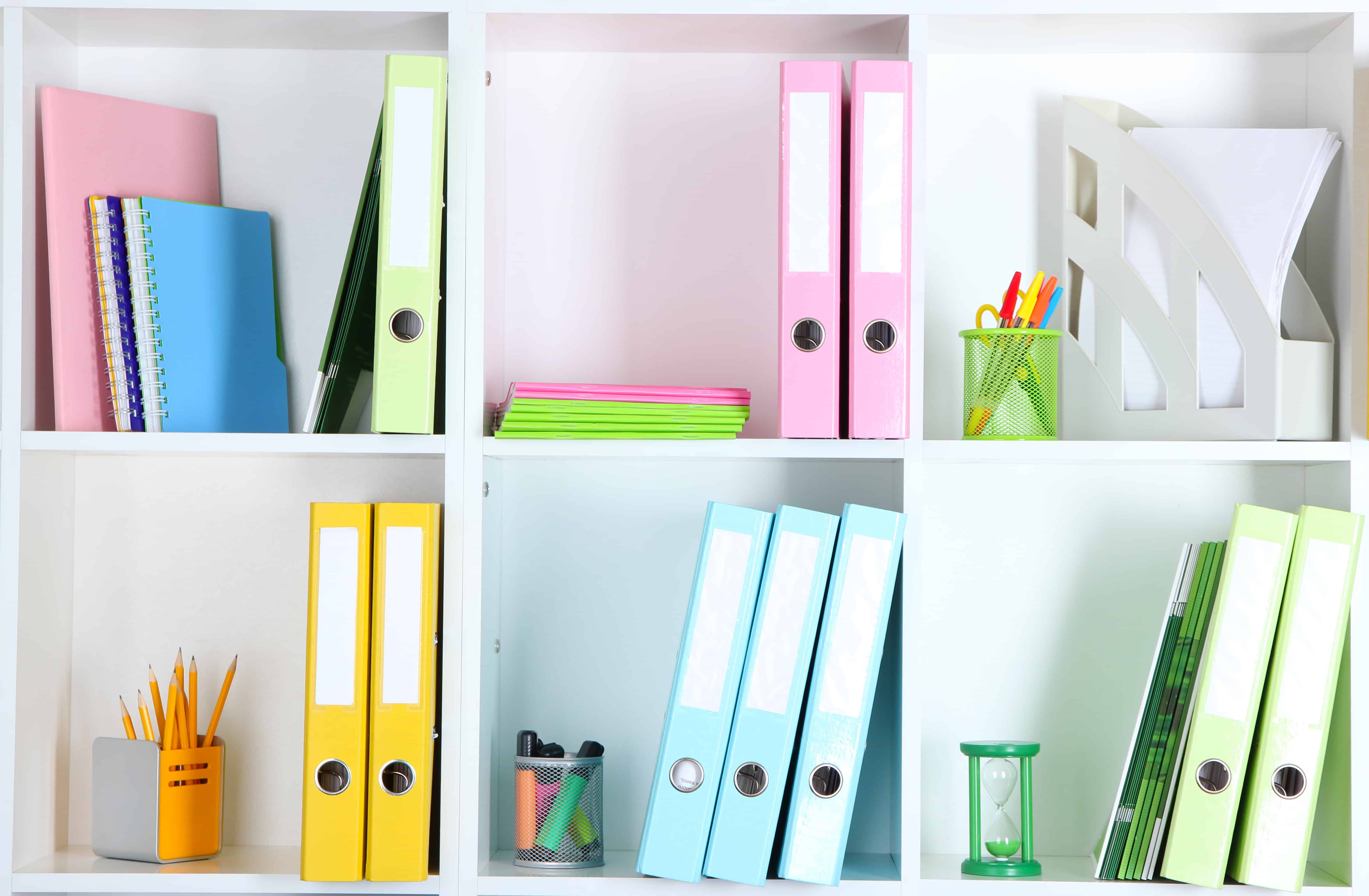 White office shelves with folders and different stationery, close up